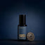 A bottle of Beardbrand Worn Denim Eau de Parfum with a vintage Union Made metal button against a dark blue background.