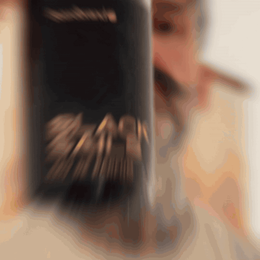 Bearded man applying Beardbrand Black Sails Cologne rollerball to his neck and showing the bottle.