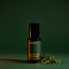 Beardbrand Short Game Eau de Parfum bottle beside fresh-cut grass on a dark green background.