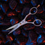 Beardbrand Trimming Scissors with the blades slightly open on shiny black stones with neon red and blue lighting accents.